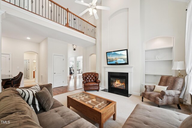 7 Teahouse Ct, Durham, NC 27707 - living area featuring a high ceiling, built in shelves, arched walkways, a ceiling fan, and a fireplace with flush hearth