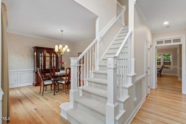 103 Rose Sky Ct, Cary, NC 27513 - stairway with wood finished floors, a chandelier, crown molding, a decorative wall, and a wainscoted wall