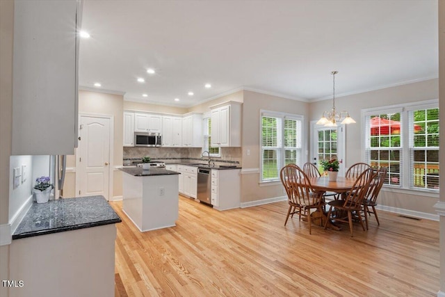 103 Rose Sky Ct, Cary, NC 27513 - kitchen featuring appliances with stainless steel finishes, a sink, light wood-style floors, crown molding, and tasteful backsplash