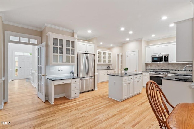 103 Rose Sky Ct, Cary, NC 27513 - kitchen with stainless steel appliances, dark countertops, light wood-style flooring, a center island, and tasteful backsplash