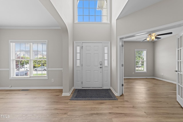 5942 Big Nance Dr, Raleigh, NC 27616 - foyer entrance with arched walkways, ceiling fan, light wood-style floors, baseboards, and ornamental molding