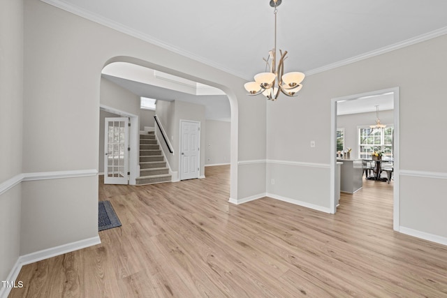 5942 Big Nance Dr, Raleigh, NC 27616 - spare room with a chandelier, arched walkways, crown molding, light wood-type flooring, and stairs