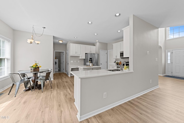 5942 Big Nance Dr, Raleigh, NC 27616 - kitchen featuring appliances with stainless steel finishes, light wood finished floors, light countertops, white cabinets, and recessed lighting