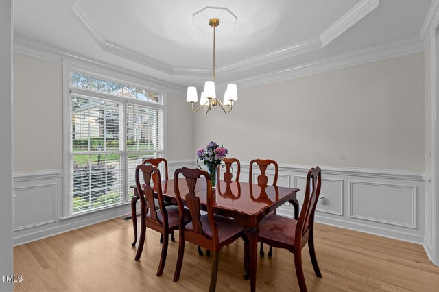 13121 Sargas St, Raleigh, NC 27614 - dining area featuring a tray ceiling, a chandelier, light wood-style floors, wainscoting, and crown molding