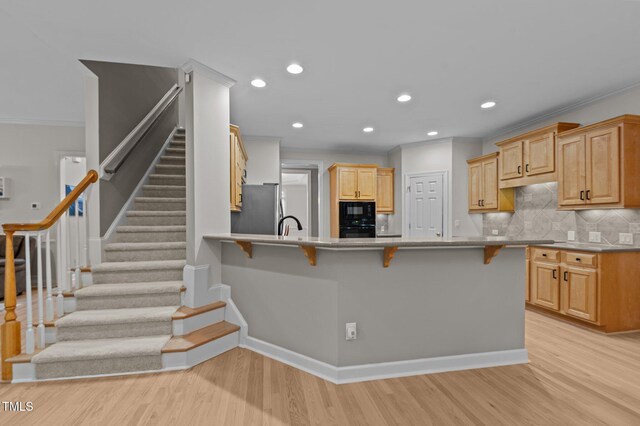 13121 Sargas St, Raleigh, NC 27614 - kitchen featuring black appliances, a breakfast bar, light wood-style flooring, backsplash, and recessed lighting