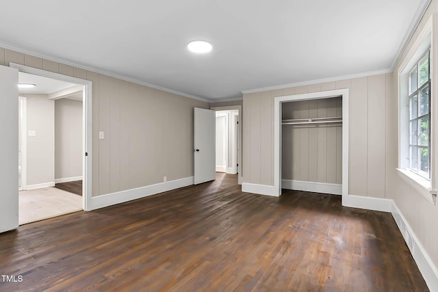 519 W Raleigh St, Siler City, NC 27344 - unfurnished bedroom featuring crown molding, dark wood-style flooring, a closet, baseboards, and a decorative wall