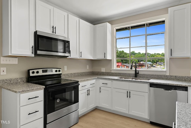 519 W Raleigh St, Siler City, NC 27344 - kitchen featuring stainless steel appliances, a sink, white cabinets, and light wood-style floors