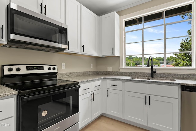519 W Raleigh St, Siler City, NC 27344 - kitchen with appliances with stainless steel finishes, a sink, white cabinets, light stone countertops, and light wood finished floors