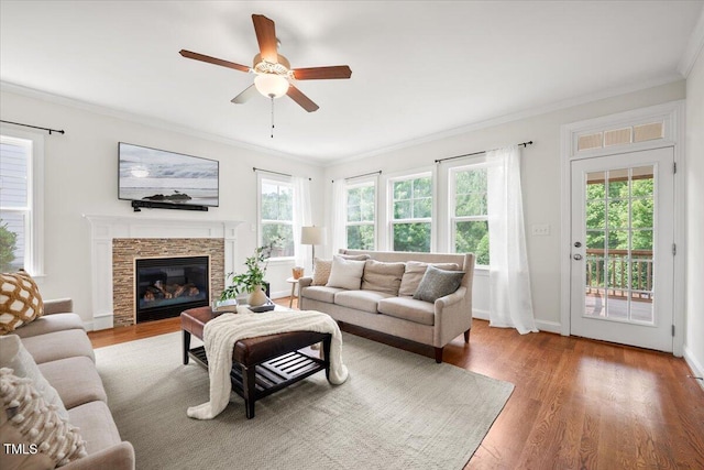 2256 Toad Hollow Trl, Apex, NC 27502 - living room featuring crown molding, ceiling fan, wood finished floors, a stone fireplace, and baseboards