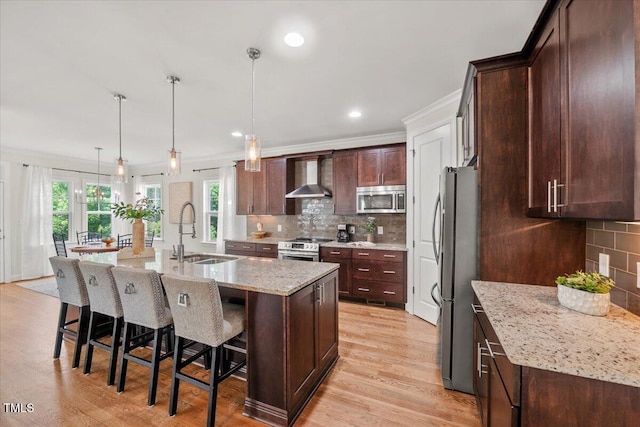 2256 Toad Hollow Trl, Apex, NC 27502 - kitchen featuring stainless steel appliances, wall chimney exhaust hood, a sink, a breakfast bar area, and crown molding