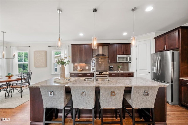 2256 Toad Hollow Trl, Apex, NC 27502 - kitchen with appliances with stainless steel finishes, wall chimney range hood, an island with sink, light wood finished floors, and a sink