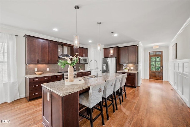 2256 Toad Hollow Trl, Apex, NC 27502 - kitchen with appliances with stainless steel finishes, a sink, wall chimney range hood, dark brown cabinetry, and crown molding