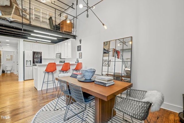 1535 Caraleigh Mills Ct Unit 210, Raleigh, NC 27603 - dining room featuring light wood-style flooring, a towering ceiling, and baseboards