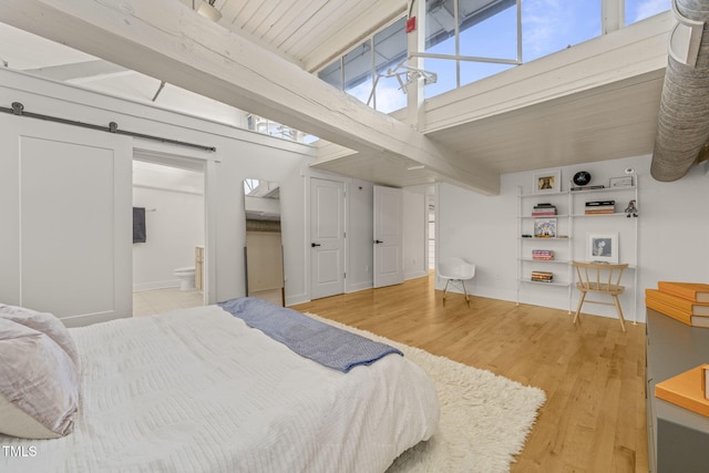 1535 Caraleigh Mills Ct Unit 210, Raleigh, NC 27603 - bedroom featuring wood finished floors, beamed ceiling, a barn door, baseboards, and ensuite bath