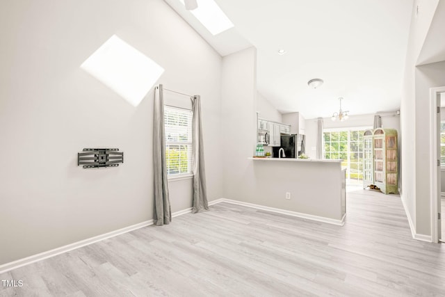 1375 Quail Cir, Creedmoor, NC 27522 - unfurnished living room featuring a skylight, light wood-type flooring, a chandelier, vaulted ceiling, and baseboards