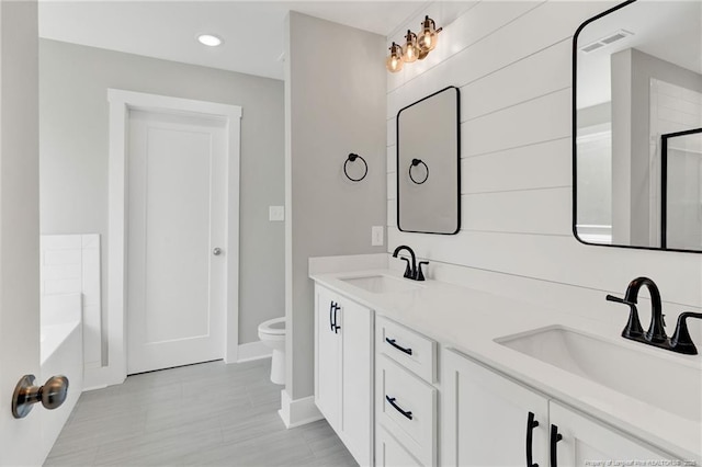 4037 Fulford Mcmillan Rd, Raeford, NC 28376 - bathroom with baseboards, toilet, double vanity, a bath, and recessed lighting