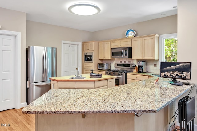 81106 Alexander, Chapel Hill, NC 27517 - kitchen featuring stainless steel appliances, a kitchen island, light brown cabinets, light wood-style floors, and a peninsula