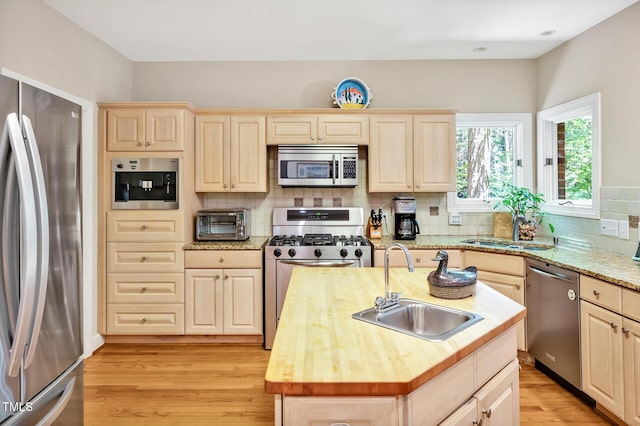 81106 Alexander, Chapel Hill, NC 27517 - kitchen with stainless steel appliances, light wood-style flooring, decorative backsplash, a center island with sink, and light brown cabinetry