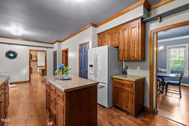1 Gatesway Ct, Durham, NC 27707 - kitchen featuring white refrigerator with ice dispenser, dark wood-type flooring, a kitchen island, brown cabinets, and ornamental molding