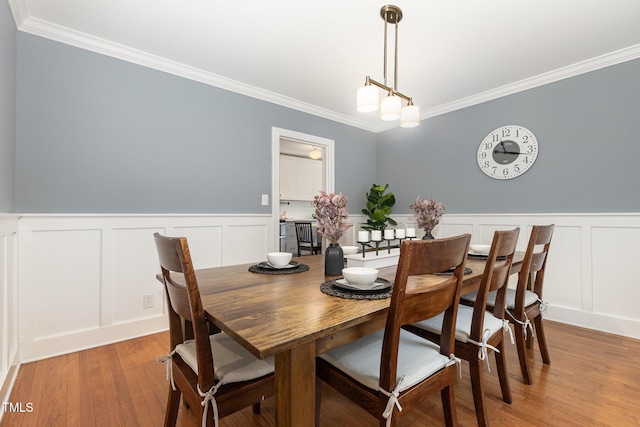 821 Onslow St, Durham, NC 27705 - dining room featuring a decorative wall, crown molding, light wood-type flooring, and wainscoting