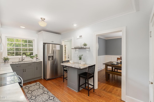 821 Onslow St, Durham, NC 27705 - kitchen featuring stainless steel fridge with ice dispenser, light wood-style flooring, a breakfast bar, gray cabinetry, and crown molding