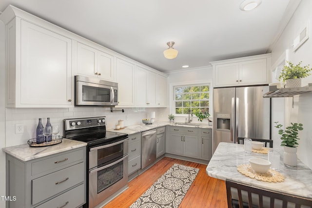 821 Onslow St, Durham, NC 27705 - kitchen with stainless steel appliances, gray cabinetry, light wood finished floors, ornamental molding, and light stone countertops