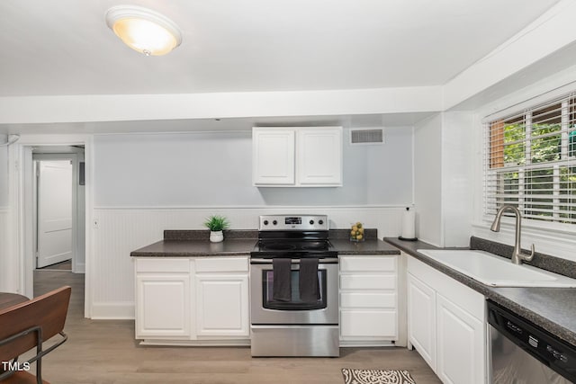 821 Onslow St, Durham, NC 27705 - kitchen featuring appliances with stainless steel finishes, white cabinetry, dark countertops, and a wainscoted wall