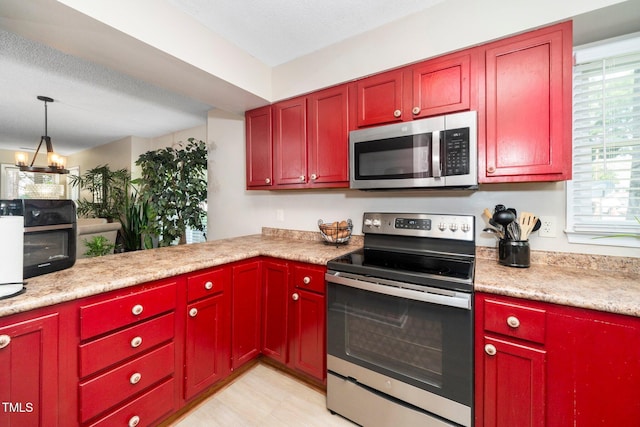 4361 Bona Ct, Raleigh, NC 27604 - kitchen with stainless steel appliances, light countertops, reddish brown cabinets, a chandelier, and pendant lighting