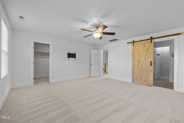531 N Person St Unit 205, Raleigh, NC 27604 - unfurnished bedroom featuring a barn door, light colored carpet, a spacious closet, and baseboards