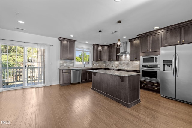 531 N Person St Unit 205, Raleigh, NC 27604 - kitchen with stainless steel appliances, wall chimney range hood, dark brown cabinets, a kitchen bar, and backsplash