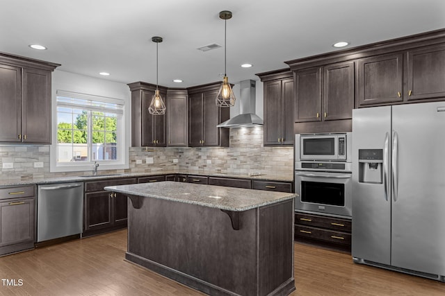 531 N Person St Unit 205, Raleigh, NC 27604 - kitchen with stainless steel appliances, wall chimney range hood, a sink, dark brown cabinetry, and wood finished floors