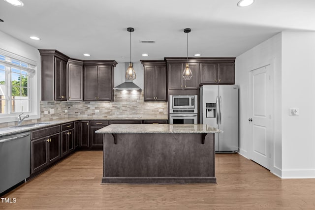 531 N Person St Unit 205, Raleigh, NC 27604 - kitchen featuring stainless steel appliances, wall chimney range hood, a sink, dark brown cabinetry, and light stone countertops
