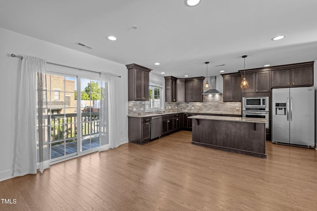 531 N Person St Unit 205, Raleigh, NC 27604 - kitchen with stainless steel appliances, wall chimney exhaust hood, dark brown cabinets, wood finished floors, and decorative backsplash