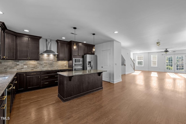 531 N Person St Unit 205, Raleigh, NC 27604 - kitchen featuring wall chimney range hood, appliances with stainless steel finishes, open floor plan, a ceiling fan, and dark brown cabinets