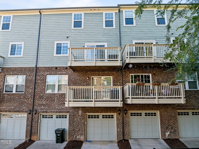 531 N Person St Unit 205, Raleigh, NC 27604 - rear view of property with brick siding, an attached garage, a balcony, and driveway