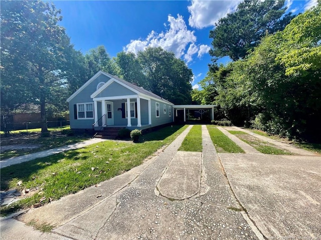 1007 Jenkins St, Lumberton, NC 28358 - view of front facade featuring concrete driveway, a front yard, view of wooded area, and a carport