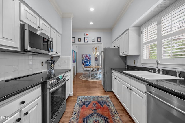441 Fieldstone Dr, Burlington, NC 27215 - kitchen with appliances with stainless steel finishes, a sink, ornamental molding, dark countertops, and white cabinetry