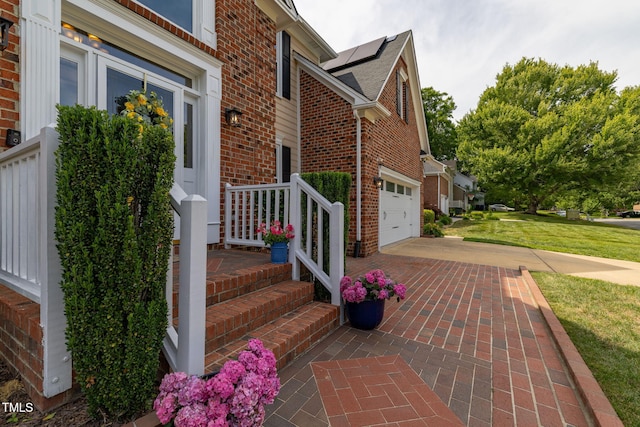 8913 Walking Stick Trl, Raleigh, NC 27615 - view of exterior entry with brick siding, a yard, concrete driveway, and solar panels