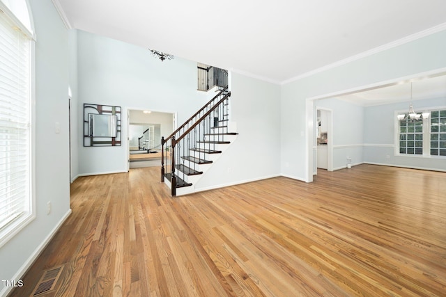 112 Sterling Ridge Way, Cary, NC 27519 - unfurnished living room with stairs, a chandelier, light wood-style flooring, baseboards, and crown molding