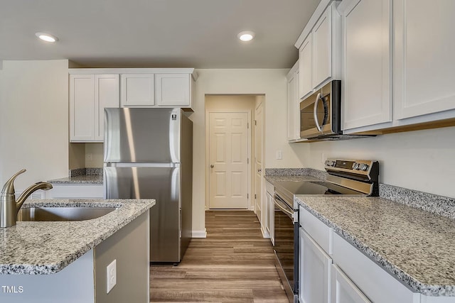 2700 Barrington Dr, Raleigh, NC 27610 - kitchen featuring appliances with stainless steel finishes, a sink, wood finished floors, white cabinetry, and light stone counters
