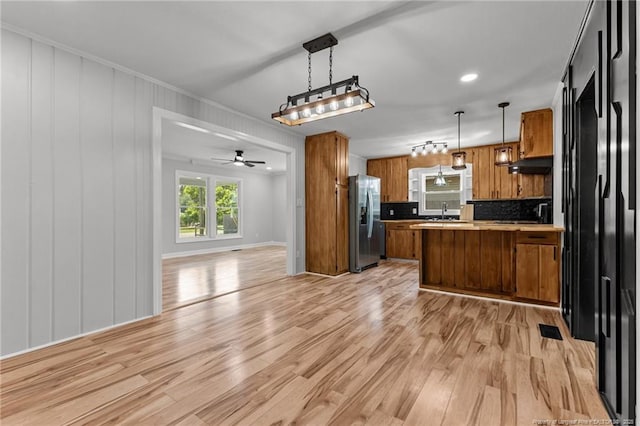 3902 Hartwell Rd, Fayetteville, NC 28304 - kitchen with stainless steel fridge with ice dispenser, open floor plan, brown cabinets, under cabinet range hood, and a peninsula
