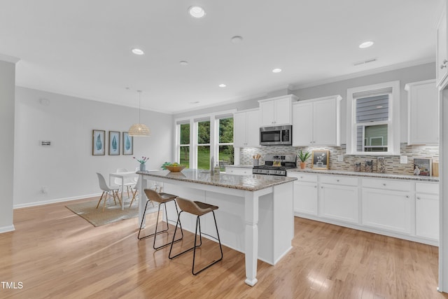 151 Bridge St, Hillsborough, NC 27278 - kitchen with appliances with stainless steel finishes, crown molding, backsplash, white cabinetry, and light stone counters