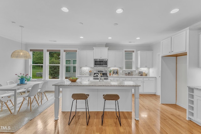 151 Bridge St, Hillsborough, NC 27278 - kitchen with stainless steel appliances, white cabinetry, backsplash, crown molding, and a kitchen bar