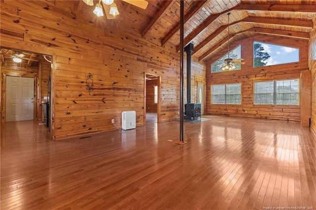 113 Atwood Ter, Stedman, NC 28391 - unfurnished living room with a wood stove, ceiling fan, high vaulted ceiling, wooden walls, and hardwood / wood-style flooring