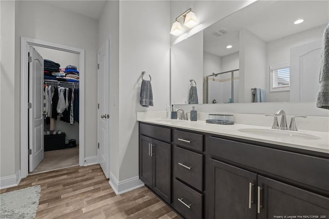 6752 Running Fox Rd, Hope Mills, NC 28348 - bathroom with a stall shower, double vanity, wood finished floors, a walk in closet, and baseboards