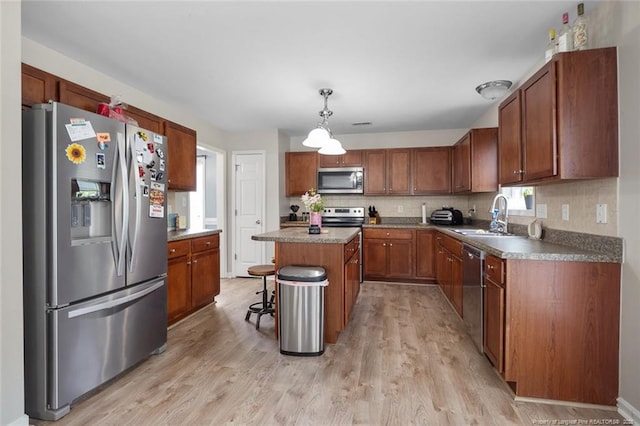 625 Fairfield Cir, Raeford, NC 28376 - kitchen featuring stainless steel appliances, a sink, light wood-style floors, a kitchen island, and decorative backsplash