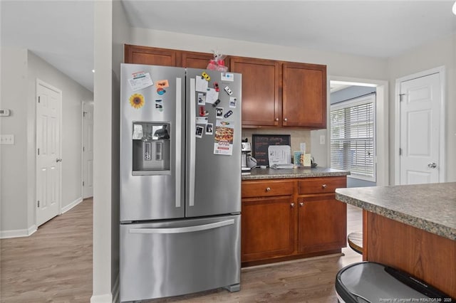625 Fairfield Cir, Raeford, NC 28376 - kitchen featuring stainless steel fridge with ice dispenser, light wood-type flooring, brown cabinetry, baseboards, and dark countertops