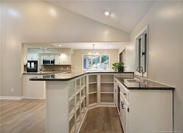 750 Mimosa Dr, Vass, NC 28394 - kitchen with a sink, stainless steel microwave, wood finished floors, vaulted ceiling, and white cabinetry