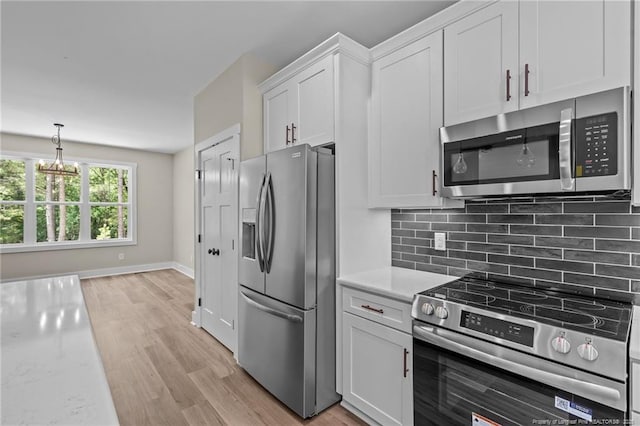 5400 Dowd Rd, West End, NC 27376 - kitchen with stainless steel appliances, light wood-type flooring, white cabinetry, decorative backsplash, and a chandelier