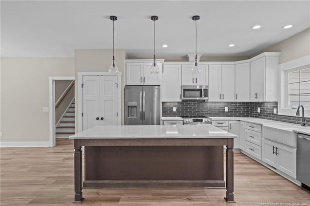 5400 Dowd Rd, West End, NC 27376 - kitchen featuring appliances with stainless steel finishes, a sink, a kitchen island, decorative backsplash, and white cabinetry